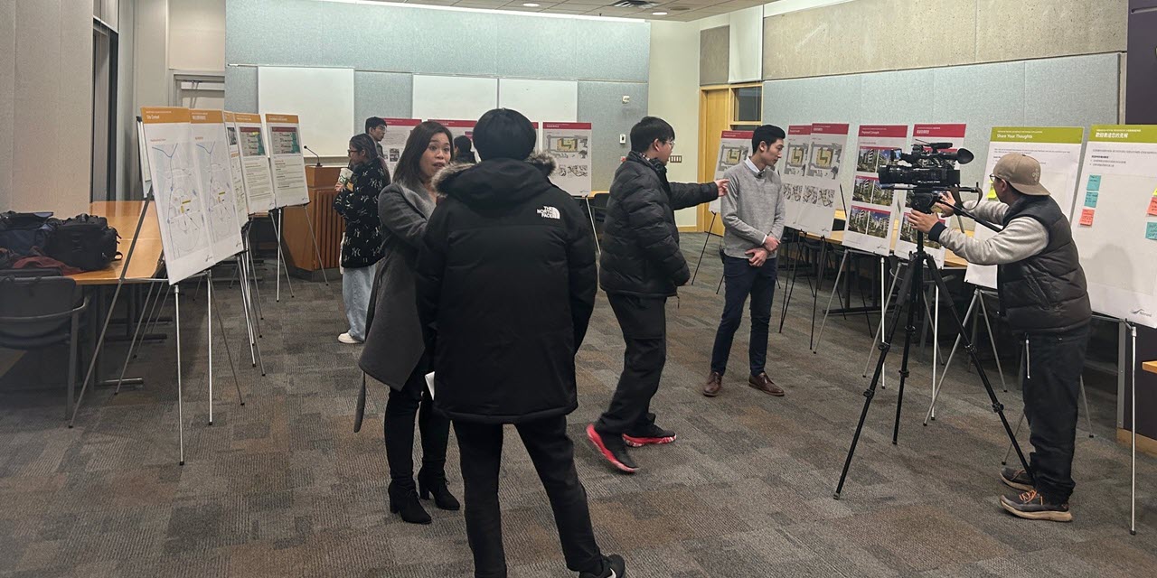 Eight people in a meeting room with info boards on display