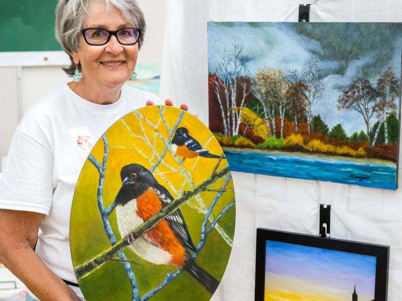 mature woman at the Steveston Community Centre holding a painting of a bird