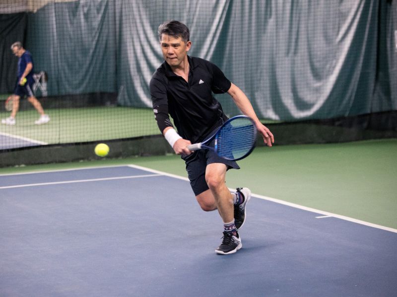 male playing tennis at the Steveston indoor Net Shed about to hit ball